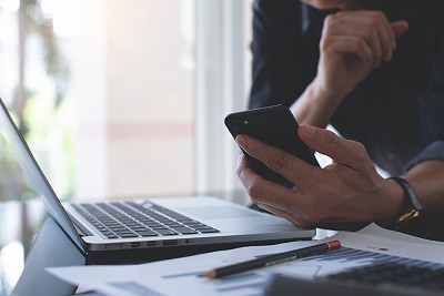 un homme d'affaires conseiller utilise son téléphone et ordinateur sur lequel il travail sur les demandes clients, conseils